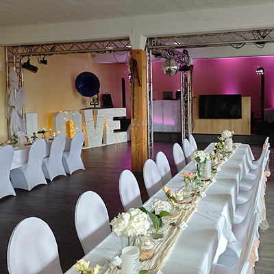 Hochzeits-DJ Eisenach mit Lichtshow im Club, lange Hochzeitstafel mit weißen Hussen und Blumendeko