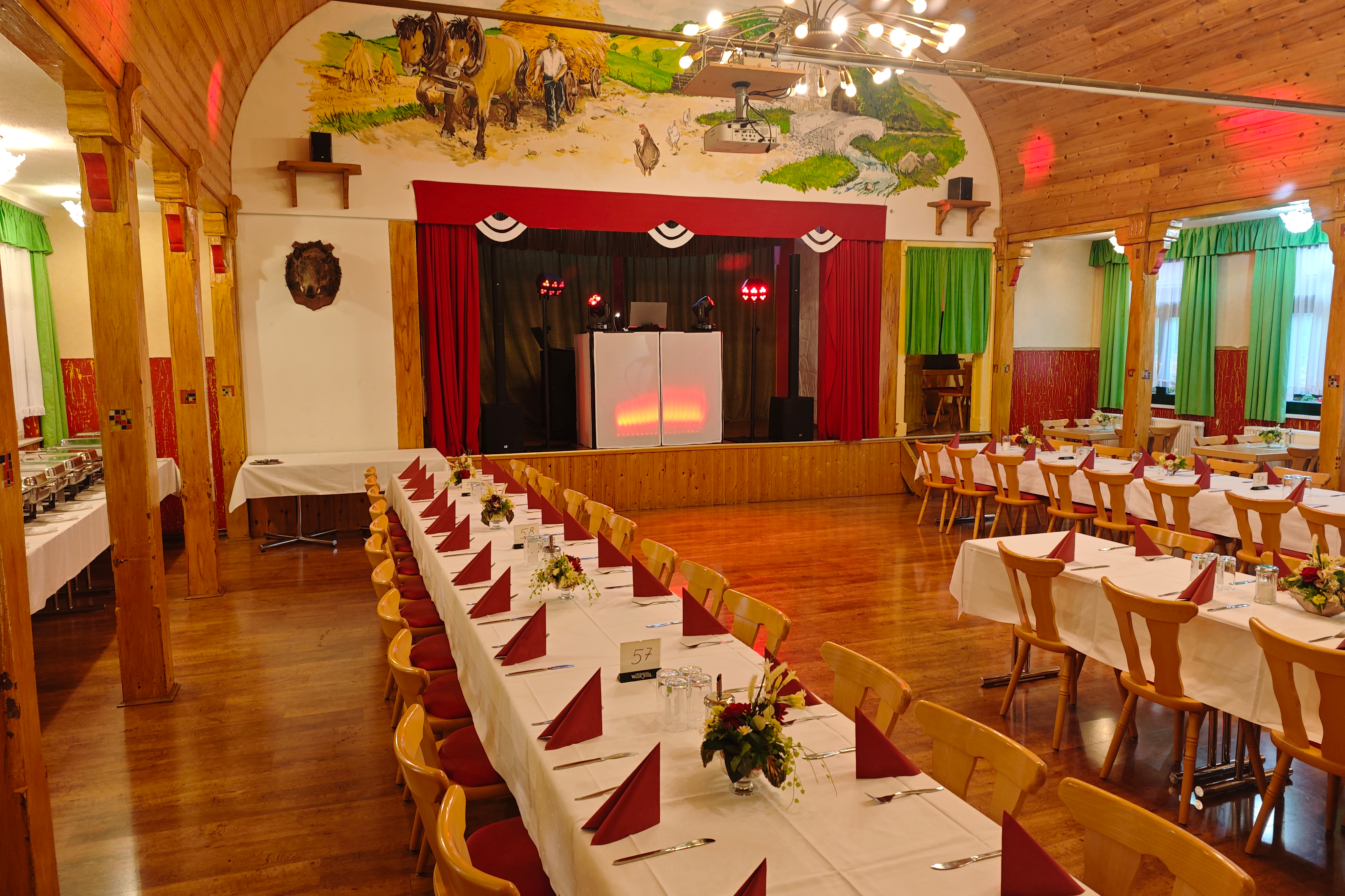 DJ Andreas beim Firmenevent im Landhotel, Bühne mit rotem Licht und festlich gedeckten Tischen