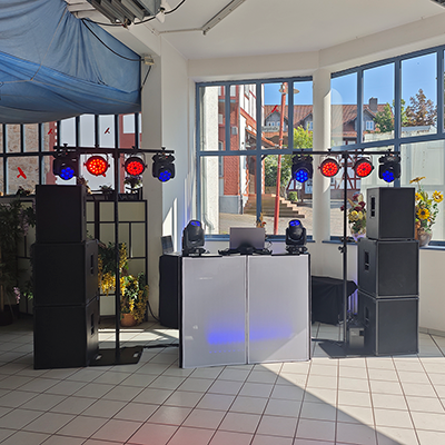 DJ Andreas Oppurg professionelles DJ-Setup mit weißem Pult, Lautsprechern und Lichttechnik in hellem Raum