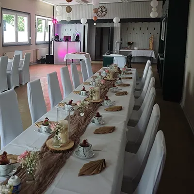 Gedeckte Festtafel im Vordergrund und pink beleuchtetes Technikpult für eine Hochzeit mit DJ Andreas im Landkreis Plaue in einem ausgebauten Gartenlokal