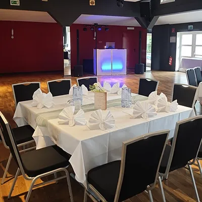 Gedeckter Tisch auf Holzparkett und blau beleuchtetes Technikpult für eine Silberhochzeit in einer Tanzschule mit DJ Andreas in Plaue