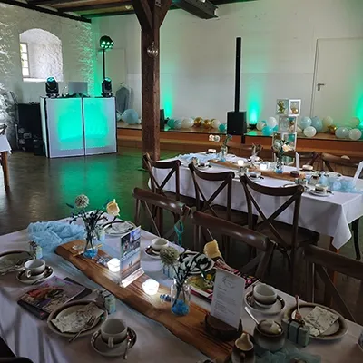 Gedeckte Tische im rustikalen Stil und grün beleuchtetes Technikpult für eine Hochzeit auf einer Wasserburg mit DJ Gerstungen